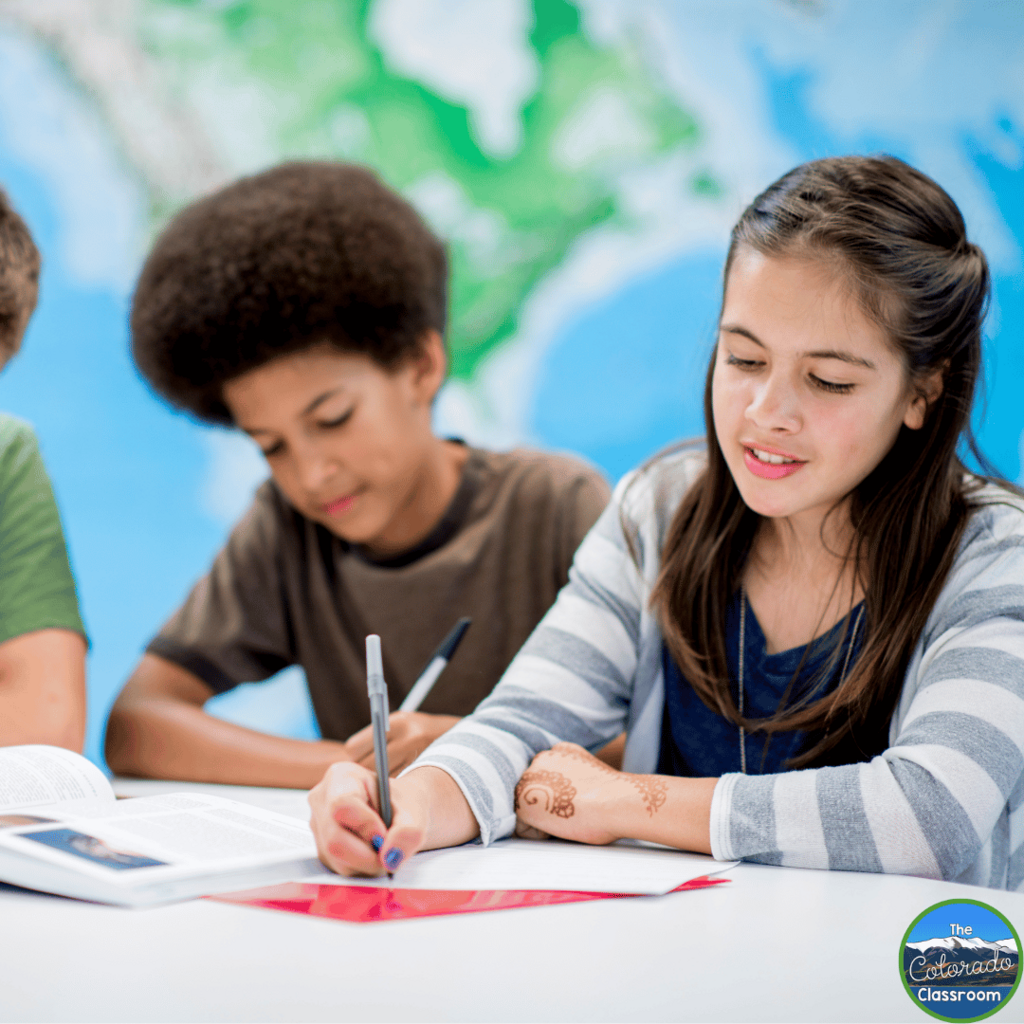 This photo shows middle school students writing at their desks in a classroom.