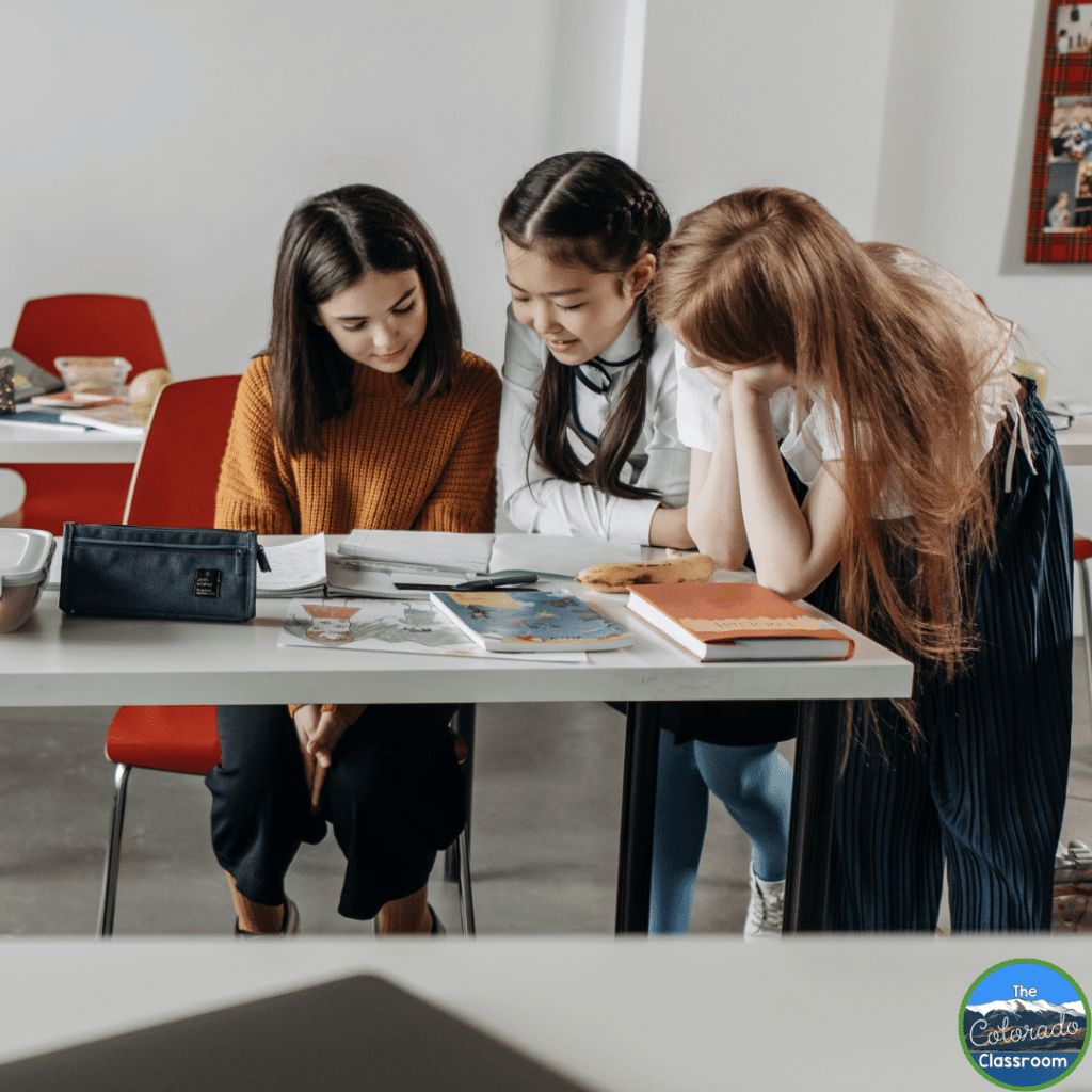 This photo shows 3 middle school students working together on a group task.