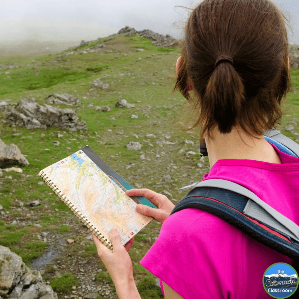 In this image, a student is using a map on a hike.